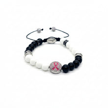 Load image into Gallery viewer, A beaded stretch bracelet featuring white and black beads, a silver-toned round charm with a pink awareness ribbon, and an adjustable black cord closure with metal sliders.