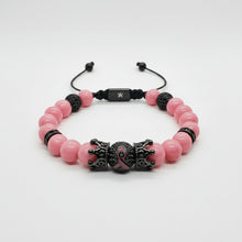 Load image into Gallery viewer, A pink and black beaded bracelet featuring a central black metal crown charm with a pink ribbon detail, set against a plain white background.