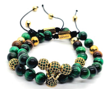 Load image into Gallery viewer, A pair of beaded stretch bracelets on a white background. The bracelets feature polished green and black beads, some with gold accents, and a central cluster of gold-toned textured beads.
